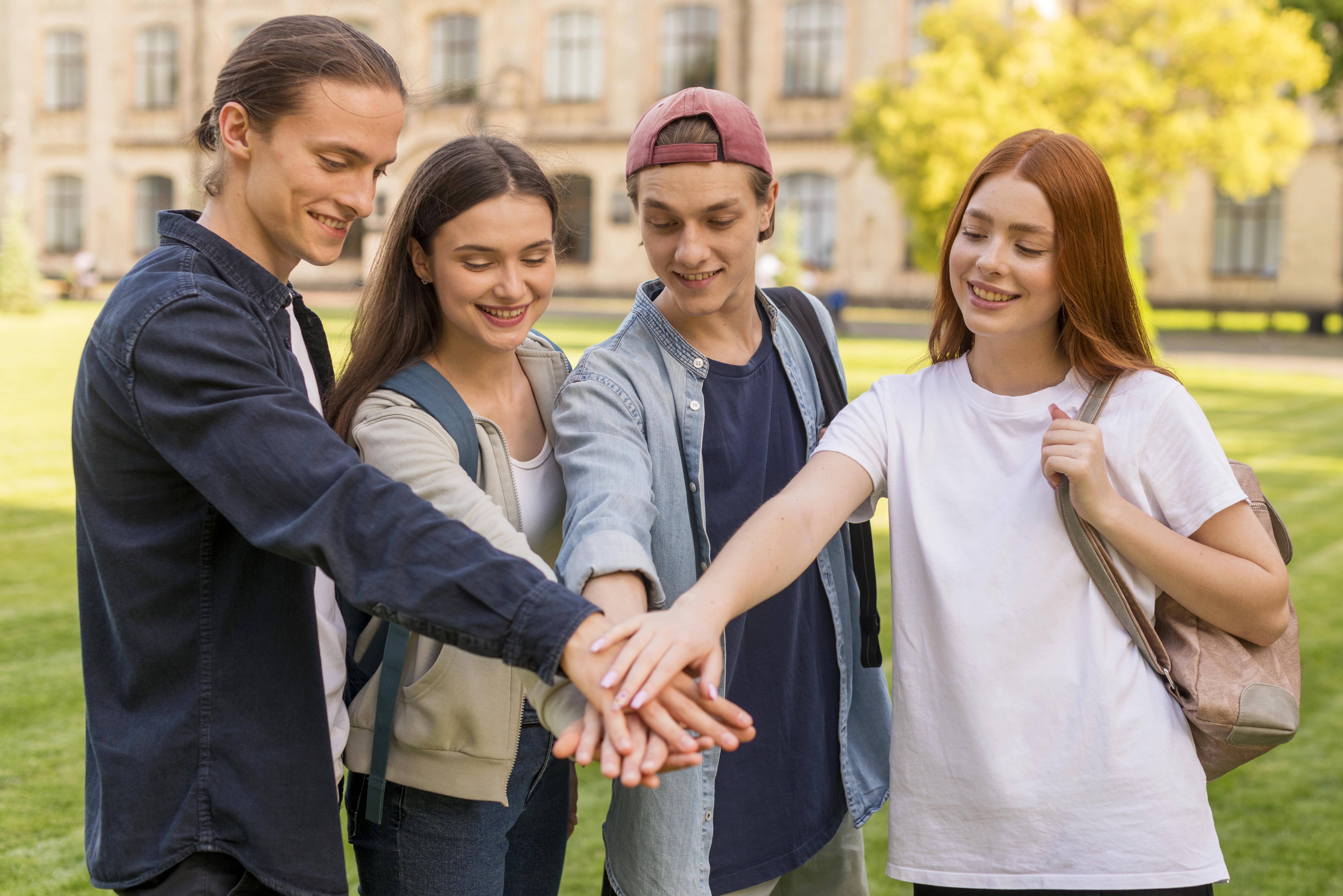 Group of international students smiling and hugging on a UK campus.
